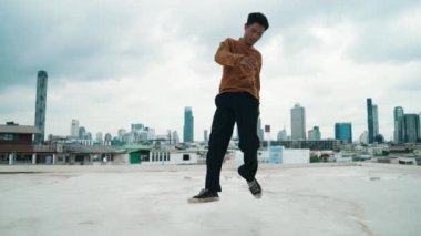 B-boy dans gösterisi çatıda sokak dansçısı ve gökyüzü dövüşçüsü, şehir manzaralı. Çekici Asyalı hipster enerjik adımlar atıyor. Break dansçı sokak dansı. Açık hava sporu 2024 hiphop..