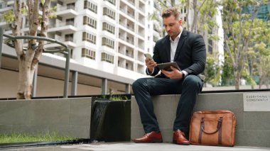 Kafkas iş adamları yeşil şehirde otururken tablet üzerinde çalışıyorlar. Uzman yönetici iş ekibiyle çalışırken finansal veri analizi yapmak ve aramak için tablet kullanıyor. Urbane.