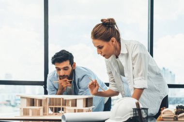 Akıllı beyaz mimar mühendis takımı ev modelini ölçmek için birlikte çalışıyor. Bir grup profesyonel iç mimar tasarım inşaatı hakkında fikir paylaşımı ve beyin fırtınası yapıyor. İzleme.