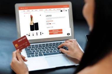 Genç bir kadın internet bankacılığı için kredi kartıyla dizüstü bilgisayar kullanıyor. Evinde online ödeme kapısı ile E ticareti yapıyor. Banka kartıyla modern ve kullanışlı online alışveriş. Blithe