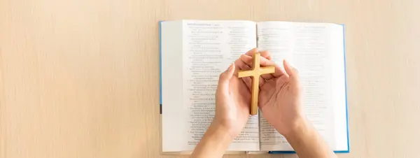 女性神信徒手持木制十字架在轻木制教堂桌上打开圣经书 顶部视图 基督教和上帝祝福的概念 温暖的背景 萌芽状态 — 图库照片
