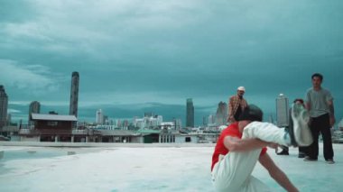 İspanyol hipster dansları şehrin mavi gökyüzü manzaralı çok kültürlü arkadaşlarıyla çevrili. Çatıda bir grup sokak dansçısı sahne alıyor. Aktif, eğlenceli, mutlu atmosfer. Açık hava sporu 2024 hiphop..