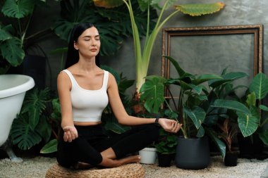 Sabah yoga ve meditasyon yapan genç bir kadın bitki yaprağıyla doğal bahçede yalnızlığın tadını çıkarıyor ve meditasyon yapıyor. Farkındalık aktivitesi ve sağlıklı zihin yaşam tarzı. Blithe