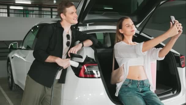 Slow Motion Pair Taking Selfie Electric Car Charging Battery Shop — Stock video