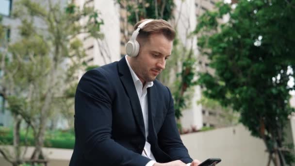 Biznesmeni Noszą Jego Słuchawki Słuchania Relaksującej Muzyki Podczas Korzystania Telefonu — Wideo stockowe