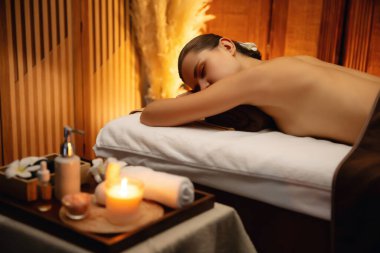 Aromaterapi masajı ambiyansı ya da spa salonu kompozisyon düzeneği bulanık kadınlara odaklı dekor mumları ve spa aksesuarları ile tatil köyü veya otel arka planında keyifli aroma spa masajı yapan. Sessiz.