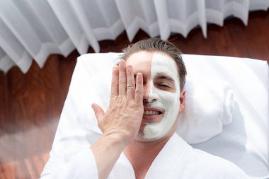 Kaplıca salonunun sakin atmosferi, insan müşterisi modern gün ışığında lüks yüz kremi masajıyla kendini yenileme zevkine kapılıyor. Yüz bakımı ve güzellik konsepti. Sessiz.