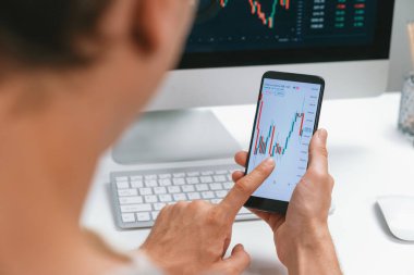 Akıllı borsa yatırımcıları ekranda akıllı telefon ile piyasa borsasını işaret ederek dizüstü bilgisayarın yanı sıra en yüksek dinamik yatırım oranını göstererek, modern işyerindeki veri planlamasına odaklanıyorlar. Bireysel.