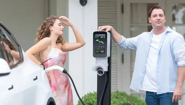Evホーム充電ステーションから電気自動車を充電する環境に配慮した幸せで素敵なカップル 住宅用電気自動車技術を将来の持続可能性に活用しました シンクロノス — ストック写真