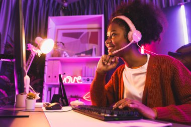 Oyun flamasının sunucu kanalı, Esport yetenekli takım oyuncusuyla yarışan Afrikalı kız ve neon renkli aydınlatma odasında online oyun izleyicileri. Siber spor ev içi aktiviteleri kavramı. Tatlandırıcı.