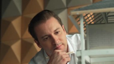 İnşaat yapısını ve hata noktalarını incelerken profesyonel mühendis yüzünün ev modeline bakması. Yetenekli proje yöneticisi ev modelini kontrol ediyor. İş tasarımı konsepti. Yönlendirici.