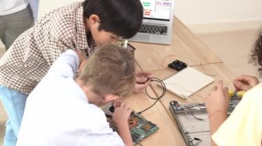 Öğretmenler tableti tutarken ve BTMM teknoloji sınıfında çevrimiçi yazılımı açıklarken ana ekranda dizüstü bilgisayar mühendisliği komut yazısıyla birlikte çalışan çeşitli öğrenci grubu. Pedagoji.