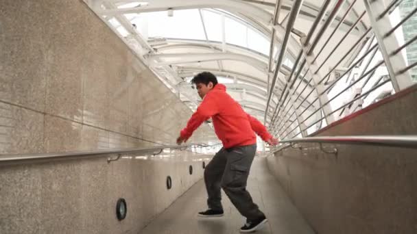 熟练的亚洲霹雳舞者在狭窄的走廊展示了男孩的舞步 专业精力充沛的嬉皮士一边走路 一边戴着耳机 自信地看着相机 2024年户外运动 神气活现 — 图库视频影像