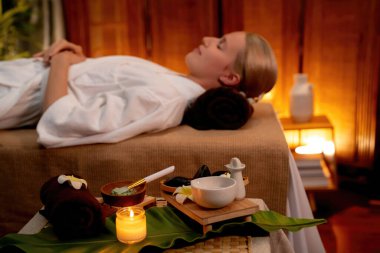 Aromaterapi masajı ambiyansı ya da spa salonu kompozisyon düzeneği bulanık kadınlara odaklı dekor mumları ve spa aksesuarları ile tatil köyü veya otel arka planında keyifli aroma spa masajı yapan. Sessiz.