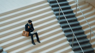 Üst düzey bir iş adamı merdivenlerde otururken başarılı bir projeyi kutluyor. Akıllı proje yöneticisinin yeni bir iş bulması, terfi alması, bilgisayar kullanarak arkadaşlarını arayarak satışları artırması. Sevinçli..