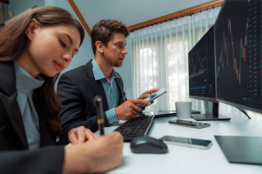 İki tüccar, dinamik borsaya danışmanlık yapıyor. İki bilgisayar ekranında yatırım yapıyor. Kadın çalışan, modern ofiste gerçek zamanlı grafikle karşılaştırıyor. Varsayım.