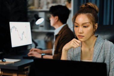 Modern ofiste gece geç saatlerde arka tarafta çalışan iş arkadaşı ile birlikte veri analizi sosyal medya çevrimiçi proje işini rapor etmek için bilgisayara odaklanan iş kadınının ciddi yüzü. İnfobahn.