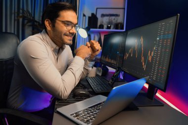 Akıllı tüccar işadamı, karanlık oda gecesinde neon ışıklı ofisteki arama pazarında yüksek kârla ekranda bilgisayar ve bilgisayar üzerinde dinamik borsa yatırımları üzerinde yoğunlaşıyor. Tahmin et..