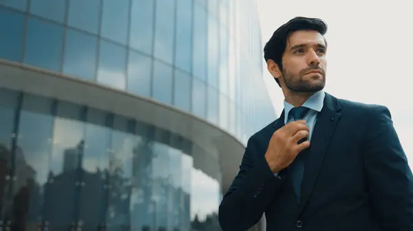 Landscape image of business man adjust tie while standing at building. Project manager wearing suit while looking around the city. Executive manager check himself before going to interview. Exultant.