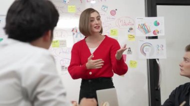 Genç ve güzel profesyonel iş kadını, yaratıcı iş toplantısında yakışıklı yönetici dinlerken zihin haritalama ve istatistiksel grafik kullanarak pazarlama fikrini kendine güvenle sunuyor. Tertemiz..