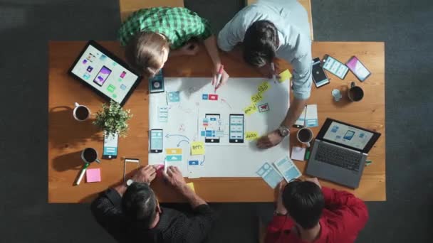 マインドマップを使用してUx Uiデザインのアイデアを共有する開発チームのタイムラウンド 携帯電話のインターフェイスアプリをブレインストーミングまたはプランニングするために一緒に働くビジネスの人々のグループのトップダウンビュー コンベンション — ストック動画