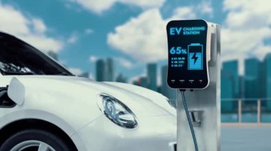 Elektrikli araba şarj istasyonuna bağlanır ve şehrin arka planında gelişmiş EV şarj cihazıyla şarj edilir. Gelecekteki yenilikçi çevre dostu enerji sürdürülebilirliği CO2 emisyonunu azaltmak için. İnceleyin