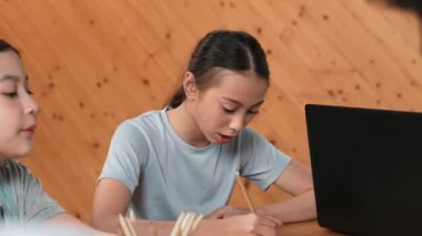 Mutlu Asyalı şirin kızın kağıda cevap yazması ya da çeşitli öğrencilerin dizüstü bilgisayarlarıyla masada çalışırken sınıfta not alması. Yaratıcı eğitim konsepti. Öğretim