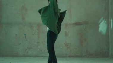 Hippi, şehir caddesinde hip-hop dinlerken kulaklık takıyor. Sokak dansçısı ayak seslerini kulaklıktan müziğe taşıyor. Açık hava sporu 2024. Çimento arka planı. Moda. Aktif stil. hiphop.