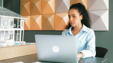 Laptop analizi ev modeli yapısını kullanan İspanyol mimar el mühendislerinin yakın çekimi. Proje yöneticisi dizüstü bilgisayarda yazarken ev modeli inşaatını kontrol ediyor. Tasarım konsepti. Yönlendirici.