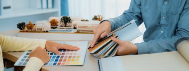 İç mimar takımı, proje yöneticisine renk örnekleri ve mimari modeli toplantı masasında sunar. Yaratıcı çalışma ve tasarım konsepti. Eline odaklan. Değiştirilmiş.