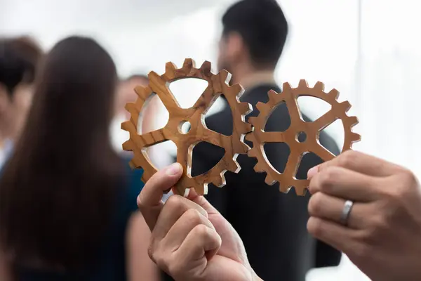 Office worker holding cog wheel as unity and teamwork in corporate workplace concept. Diverse colleague business people showing symbol of visionary system and mechanism for business success. Concord