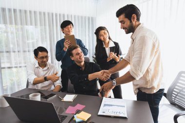 Çeşitli ofis çalışanları stratejik iş pazarlama toplantısı üzerine anlaşma yaptıktan sonra el sıkışıyor. Takım çalışması ve olumlu tutum verimli ve destekleyici bir iş yeri yaratır. Tedbirli