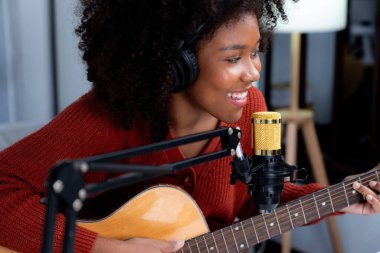 Güzel Afrikalı kadın etkilerinin portre sunucusu kanalı yayında gitar çalarak şarkı söylüyor. Canlı sosyal medyada müzik blogcusu zamanı. Ses yaratıcısı kavramı. Tatlandırıcı.