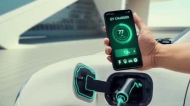 Akıllı telefon uygulaması ekranda dijital EV araba aküsünün şarj istasyonu ile şarj olurken durumunu gösteriyor. Otomobil kullanımı kavramı için alternatif sürdürülebilir ve temiz enerji. İnceleyin