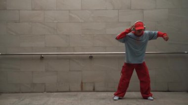 Yakışıklı koreograf gri arka planda sokak dansı yapıyor. Genç çekici erkek dansçı şık kıyafetler giyerken gösteri yapıyor. Hareketli bir adım. Uzayı kopyala Açık hava sporu 2024. Yumuşak bir şekilde..