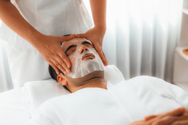 Kaplıca salonunun sakin, modern gündüz atmosferi. Kadın müşteri yüz maskesi takarak kendini yenilemeye çalışıyor. Yüz bakımı ve güzellik kozmetolojisi prosedürü. Sessiz.