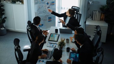 Akıllı yönetici projesinin üst görünümü beyaz tahtaya zihin haritası ve finansal grafik ile işaret ediyor ve çeşitli yatırımcılar hisse yatırım grafiğini dinleyip analiz ederken pazarlama fikrini açıklıyor. Müdürlük.