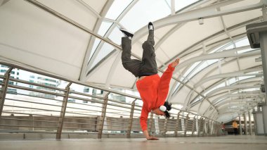 Hipster 'ın kulaklık taktığı ve enerjik adımlar atarken hip hop dinlediği bir sahne. Break dansçı dondurucu poz veriyor. Sokak dansı. Modern yaşam tarzı. Açık hava sporu 2024. Yumuşak bir şekilde..