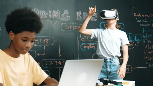 stock image Smart african student programing and coding innovative system while caucasian girl enter in metaverse or virtual world by using VR or head set at blackboard in STEM technology classroom. Edification.