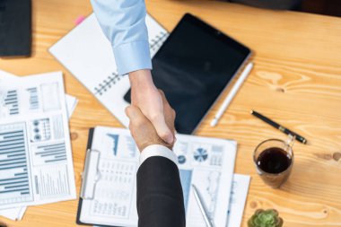 Toplantı odasında iş arkadaşıyla tokalaşan iki işadamı neşeli bir alkış veriyor. Analistlerden oluşan ekip, iş stratejik performansında kaydedilen önemli ilerlemeyi kutluyor. Çok titiz.