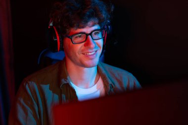 PC dövüş oyununda Esport 'ta oyun çubuğuyla oynayan gülümseyen genç oyun flaması takımı, kırmızı neon ışıklı modern odada gelecek için strateji planlamasında rakiplerini kazanmaya çalışıyor. Toplayıcı.