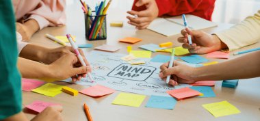 Yaratıcı iş adamları, zihin haritalama kullanarak pazarlama stratejisi ve iş planı hakkında beyin fırtınası yapıyorlar. Girişim ekibi kağıda yazmak için birlikte çalışır. Eline odaklan. - Yakın çekim. Değiştirilmiş.