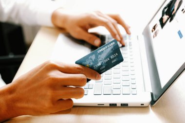 Genç adam, laptop bilgisayar başvurusu ya da web sitesinde online alışveriş yapmak için kredi kartı kullanıyor. E-ticaret ve online alışveriş konsepti. uds