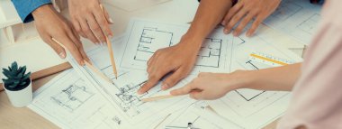 Mimari planlar toplantı masasında dağıtılırken profesyonel mimar el çabukluğu planlara işaret ediyor. Yaratıcı tasarım takım çalışması tartışma konsepti. Üst Manzara. Filizlenen.