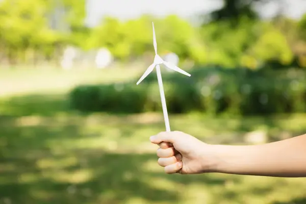 Little boy holding windmill or wind turbine mockup model to promote eco clean and renewable energy technology utilization for future generation and sustainable Earth. Gyre