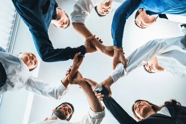Business team joining hand in circular together symbolize successful group of business partnership and strong collective unity teamwork in diverse culture community workplace. Prudent