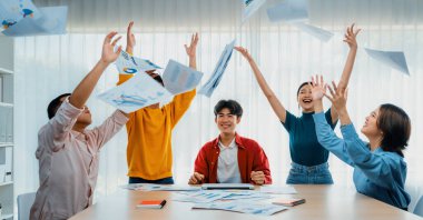 Heyecanlı ve mutlu bir şirket çalışanı başarılı bir iş yaptıktan sonra kutlama yapıp havaya kağıt fırlatıyor. Takım çalışması ve pozitif çevre üretken ve destekleyici bir işyeri yaratır. Sinerjik