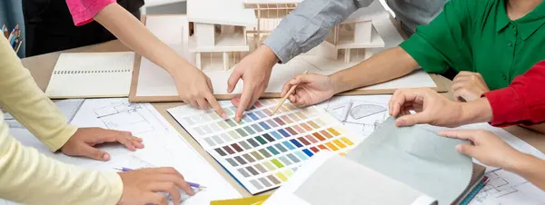 熟练的设计团队讨论房屋建造 而室内设计人员则用房屋模型和蓝图在色彩调色板上指出合适的颜色 顶部视图 — 图库照片