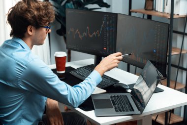 Piyasa stoku grafiği üzerinde çalışan genç profesyonel tüccar ev ofisindeki gerçek zamanlı ekranlara yatırım yaparak önemli döviz kuru kavramları yazarak analiz ediyor. Toplayıcı.