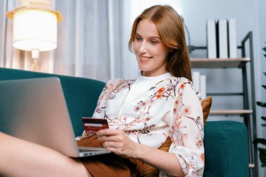 Genç mutlu kadın internetten alışveriş yaparak ürün satın alırken aynı zamanda internet üzerinden online ödeme sistemi ile çevrimiçi mağaza platformundan en yüksek siber güvenlik tarafından korunan ürünler sipariş ediyor.